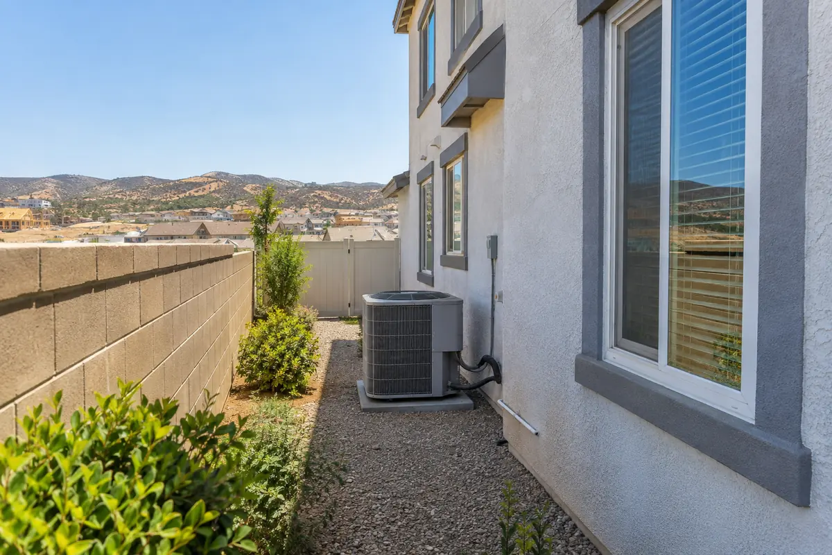 Condenser in a narrow side yard beside a two-story house and a block wall, ac maintenance in Garland, TX